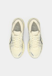 Μπεζ αθλητικά παπούτσια με υφασμάτινη επάνω επιφάνεια και ανακλαστικές λεπτομέρειες. Διαθέτουν μαλακό κολάρο, κλείσιμο με κορδόνια και αφράτη σόλα.