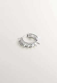 Pendiente de aro de plata con picos salientes y una fila de pequeñas cuentas a lo largo de un borde. Textura metálica suave, forma circular y diseño llamativo.