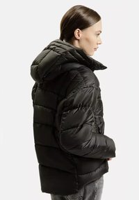 Czarna kurtka puchowa z kapturem, charakteryzująca się pikowanym wzorem, gładką fakturą i luźnym krojem. Regulowane mankiety i boczne kieszenie.