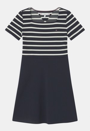 Sukienka w paski z krótkim rękawem, z granatową dolną częścią i jasnymi paskami. Posiada dekolt w serek oraz małe logo na piersi.