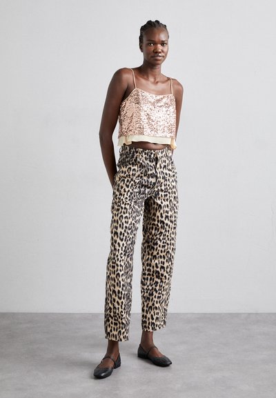 Top cropped de lantejoulas cor de rosa com bainha com volantes, combinado com calças de cintura alta de padrão de leopardo. Sapatos planos pretos completam o visual.