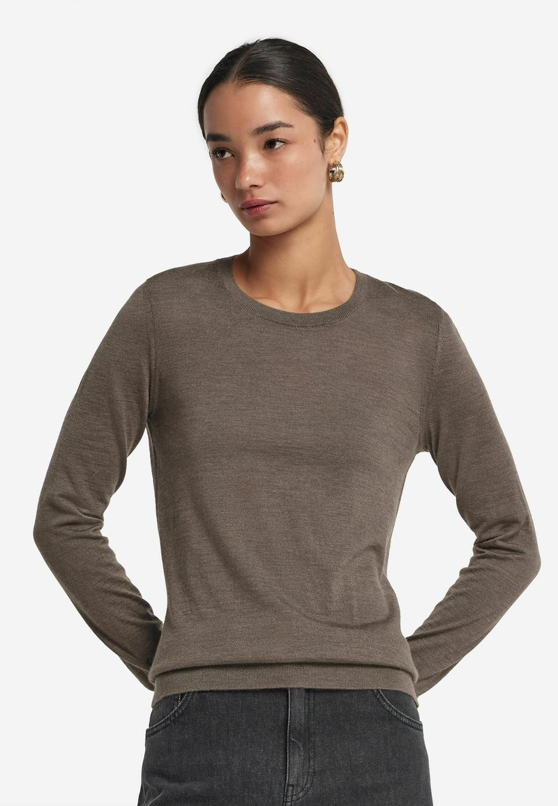 Brązowy, długi sweter z rękawami w dopasowanym fasonie z okrągłym dekoltem i prążkowanymi mankietami. Wykonany z miękkiego, lekkiego materiału.