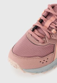 Baskets de sport roses avec tige en mesh, accents texturés et semelle en caoutchouc. Comprend des lacets plats et des détails de couture orange contrastants.