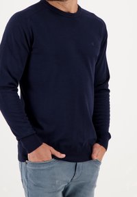 Marinblå crewneck sweatshirt i mjukt material, med ribbade ärmslut och nederkant, slim fit-design med minimal tryck på bröstet.