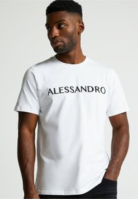 Camiseta de algodón blanca con el texto "ALESSANDRO" bordado en negro en el pecho, mangas cortas y cuello redondo.