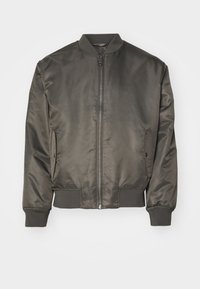 Donkergroene bomberjack van glad, glanzend materiaal. Voorzien van geribbelde manchetten, een ritssluiting aan de voorkant en zijzakken. Eenvoudig ontwerp.