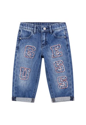Jeans in denim blu con un lavaggio chiaro, caratterizzati da grandi lettere ricamate 'G', 'U', 'E', 'S', 'S' in colori a contrasto sul davanti.