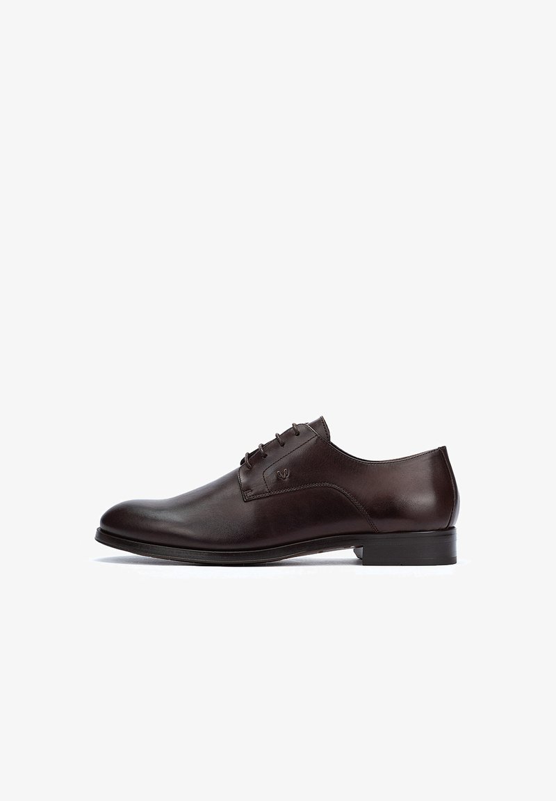 Zapato de vestir de cuero marrón con acabado suave, punta redondeada, diseño de cordones y acentos mínimos para una apariencia clásica. Suela de goma para tracción.