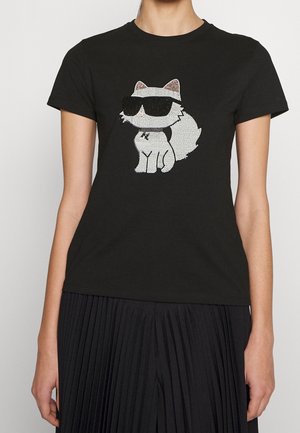 Camiseta negra ajustada con un gráfico de zorro blanco en el pecho, que lleva gafas de sol negras hechas de pedrería.