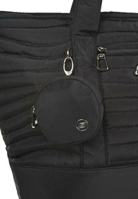 La bolsa de tote acolchada negra presenta un bolsillo cilíndrico con cremallera unido con un clip de metal. Superficie texturizada con detalles de costura distintivos.