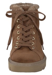 Stivale alla caviglia in suede marrone con bordo in pelliccia sintetica, lacci piatti, occhielli dorati e una spessa suola piatta color cammello. Presenta un design a punta rotonda.