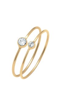 Gold-Doppelring mit zwei klaren Edelsteinen, einem größeren und einem kleineren, die in runden Metallfassungen gesetzt sind. Glatte, polierte Oberfläche.