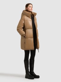Tan puffer coat with a high collar, featuring a padded design and side pockets. Paired with black leggings and knee-high black boots.