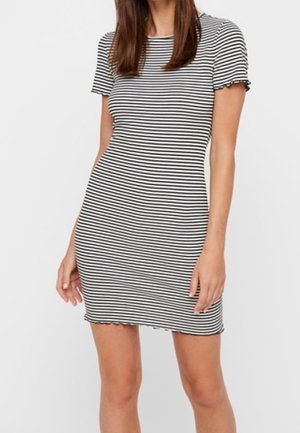 Femme portant une robe courte ajustée à rayures horizontales noires et blanches, avec des manches courtes et des ourlets festonnés.
