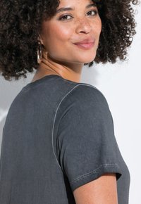 Grå kortærmet top med blød tekstur og subtile syningsdetaljer. Designet har en afslappet pasform og en rund halsudskæring.