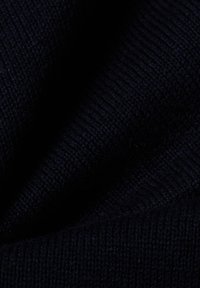 Marine gebreide stof die een gladde textuur laat zien met subtiele ribbels. Zachte en uniforme kleur, stevig geweven garen zonder zichtbare patronen.