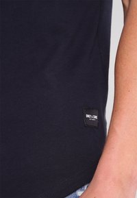 Tummansininen t-paita pehmeästä puuvillasta, jossa pyöreä pääntie ja sivussa oleva "ONLY & SONS" -merkki. Kangas on sileäpintainen.