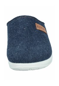 Pantofole di feltro blu navy con suola bianca liscia, dotate di un'etichetta in pelle marrone con la scritta "FLY FLO". Forma arrotondata e texture morbida.