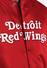 Rote Satinjacke mit weißem, gesticktem "Detroit Red Wings"-Text. Verfügt über einen Druckknopfverschluss und eine glatte Textur für einen klassischen sportlichen Look.