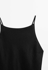 Haut noir sans manches avec fines bretelles et encolure droite sur fond blanc.