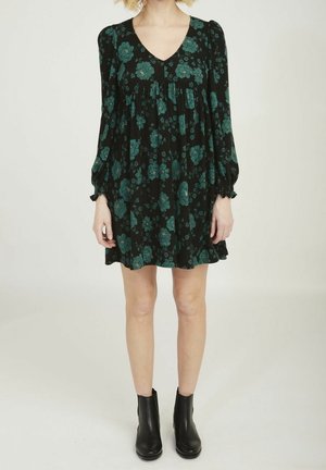 Zwarte bloemenjurk met teal bloemen, v-hals, lange puffmouwen met elastische manchetten en een wijde rok. Gemaakt met zwarte enkellaarsjes.