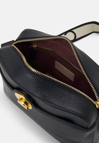Schwarze Leder-Umhängetasche mit strukturiertem Äußeren, goldenen Beschlägen und einem bordeauxfarbenen Innenfutter. Verfügt über einen Reißverschluss und ein Innenetikett mit Markenlogo.