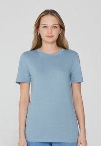 Světle modré tričko s krátkým rukávem vyrobené z měkkého materiálu. Má kulatý výstřih a volný střih, bez vzorů nebo akcentů.