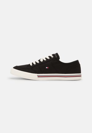 Czarny niskoprofilowy sneaker z białą podeszwą i sznurowadłami, z małym logo w kolorach czerwonym, białym i niebieskim po boku oraz pasiastym detalem na podeszwie.