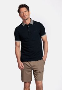 Marineblauwe polo met gestreepte kraag en mouwen, slanke pasvorm, gemaakt van een katoenmix. Gepaard met beige shorts, voorzien van zijzakken.