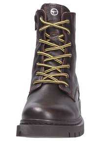 Botín de cuero marrón con cordones amarillos, puntera redonda, cuello acolchado y suela de goma texturada. Cuenta con una cremallera lateral para facilitar su puesta.