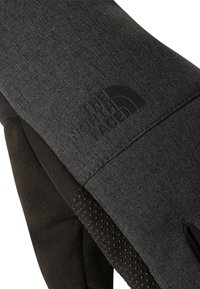 Gants noirs en tissu texturé avec une paume noire lisse. Présentent un logo en relief et de petits points antidérapants sur la paume pour une texture améliorée.