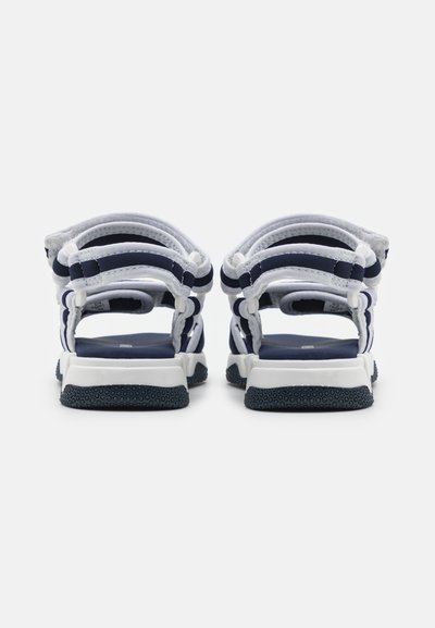 Športové sandále s bielymi a námorníckymi textilnými popruhmi, polstrovanou námorníckou stielkou a štruktúrovanou čiernou gumovou podrážkou. Zadný pohľad s otvoreným dizajnom pätky.