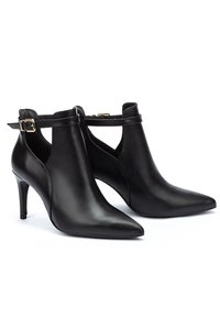 Botines de cuero negro hasta el tobillo con puntera puntiaguda, tacón afilado y acento de hebilla. Presentan un diseño elegante y una textura suave.