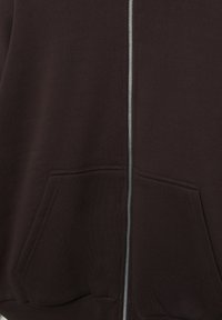 Donkerbruine zip-up hoodie met twee voorzakken en een zichtbare zilveren rits die in het midden loopt.