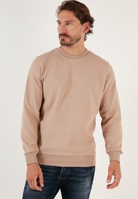 Felpa in cotone beige con superficie strutturata, colletto rotondo e polsini a costine. Dettaglio a punto V evidente sul colletto. Vestibilità casual.