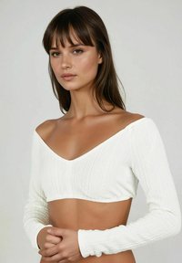 Weißes, strukturiertes Cropped-Top mit langen Ärmeln und tiefem V-Ausschnitt, das ein geripptes Muster im gesamten Stoff aufweist.