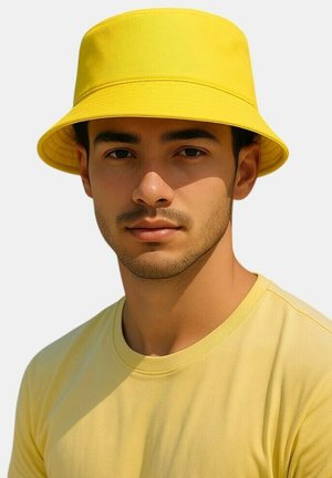 Geel stoffen bucket hat met een brede rand en een gestructureerd oppervlak, gedragen boven een bijpassende geel kortemouwenshirt.