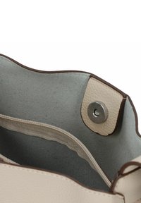 Interno di una borsa in pelle beige con texture liscia, accentata da dettagli marroni e una tasca con zip. Design aperto con bordo arrotondato.