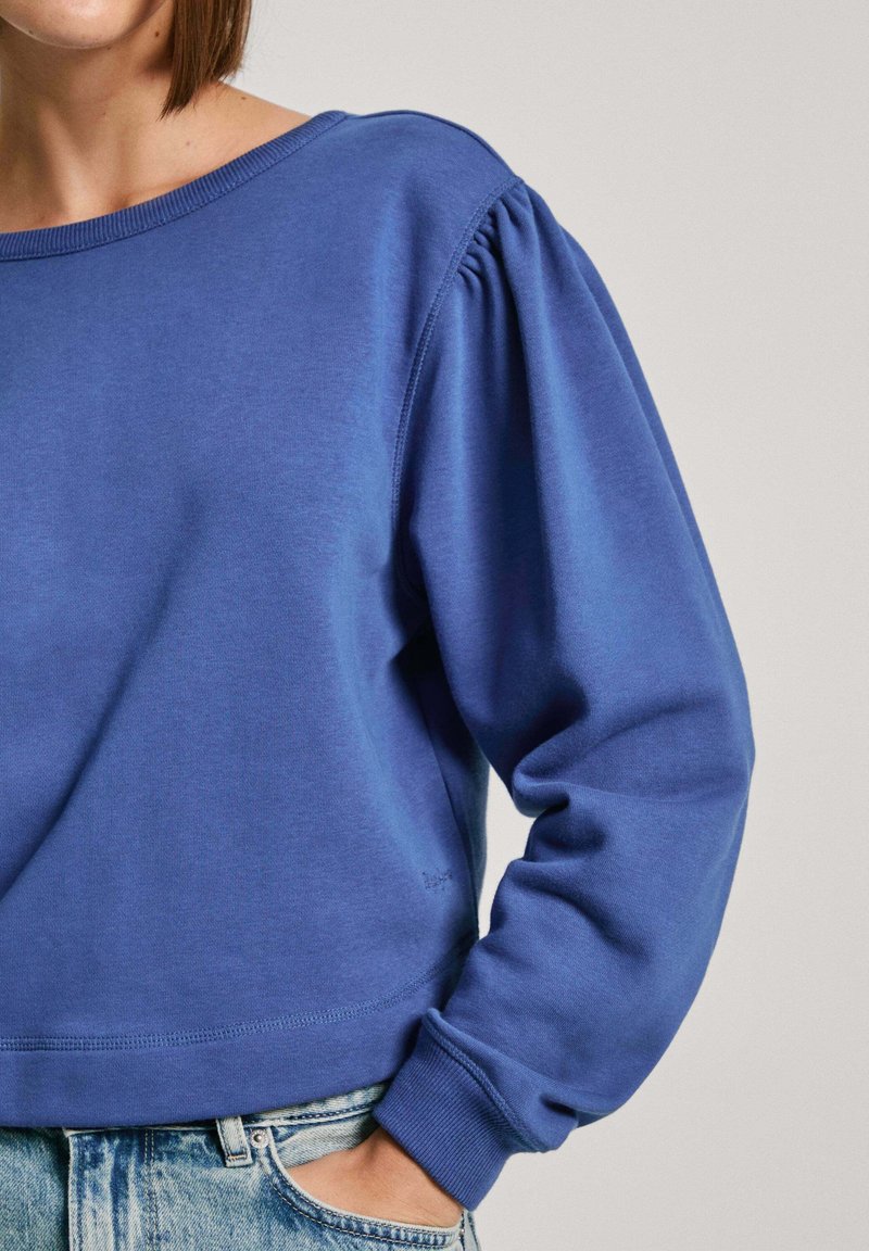 Blauwe sweatshirt met een ronde hals, gepofte mouwen en geribde manchetten. Gemaakt van zacht materiaal met een relaxte pasvorm en minimale stikseldetails.