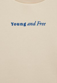 Gaiši beidzama džemperis ar apaļu izgriezumu, priekšpusē ar zilu izšuvumu vārdiem "Jauni un Brīvi". Gluda auduma tekstūra.