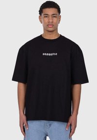 Svart oversized t-skjorte med korte ermer, med hvit tekst "DROPSIZE" på brystet, laget av myk bomullsstoff.