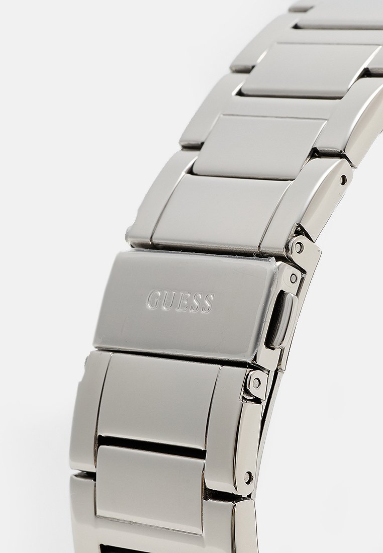 Orologio in acciaio inossidabile argentato con chiusura pieghevole in metallo, caratterizzato da una finitura lucida e dal nome del marchio "GUESS" inciso sul bracciale.