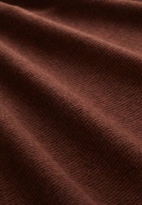 Texturovaná látka v bohaté hnědé barvě, s jemnými žebry a různou tloušťkou, která vytváří měkký, tkaný vzhled.
