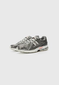 Gray athletic shoes with a mesh upper, featuring a reflective design, white midsole, and textured rubber outsole. Orange accent near the heel.