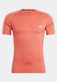 Camisa atlética de manga corta en color coral, hecha de tejido suave y elástico. Presenta el logo de Adidas en blanco y tres franjas blancas a lo largo de los hombros.