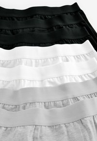 Fyra par ribbade elastiska midjeband underkläder ordnade i lager, i färgerna svart, mörkgrå, ljusgrå och vit.