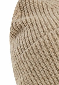 Beige knitted hat with a textured ribbed pattern. The material appears soft and is folded at the cuff, showcasing a subtle color variation.