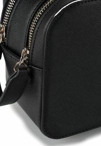 Zwarte synthetische handtas met een gestructureerde afwerking, afgeronde hoeken, dubbele ritssluiting en zilverkleurige hardware-accenten. Compact en gestructureerd ontwerp.