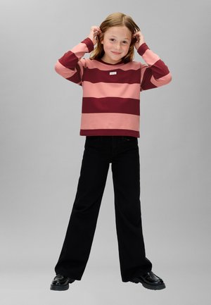 Felpa a maniche lunghe a righe rosa e bordeaux, abbinata a pantaloni neri svasati e scarpe nere. Design semplice con scollo rotondo.