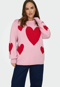Růžový pletený svetr s velkými červenými srdci na přední straně a rukávech, s žebrovanými manžetami a volným střihem.